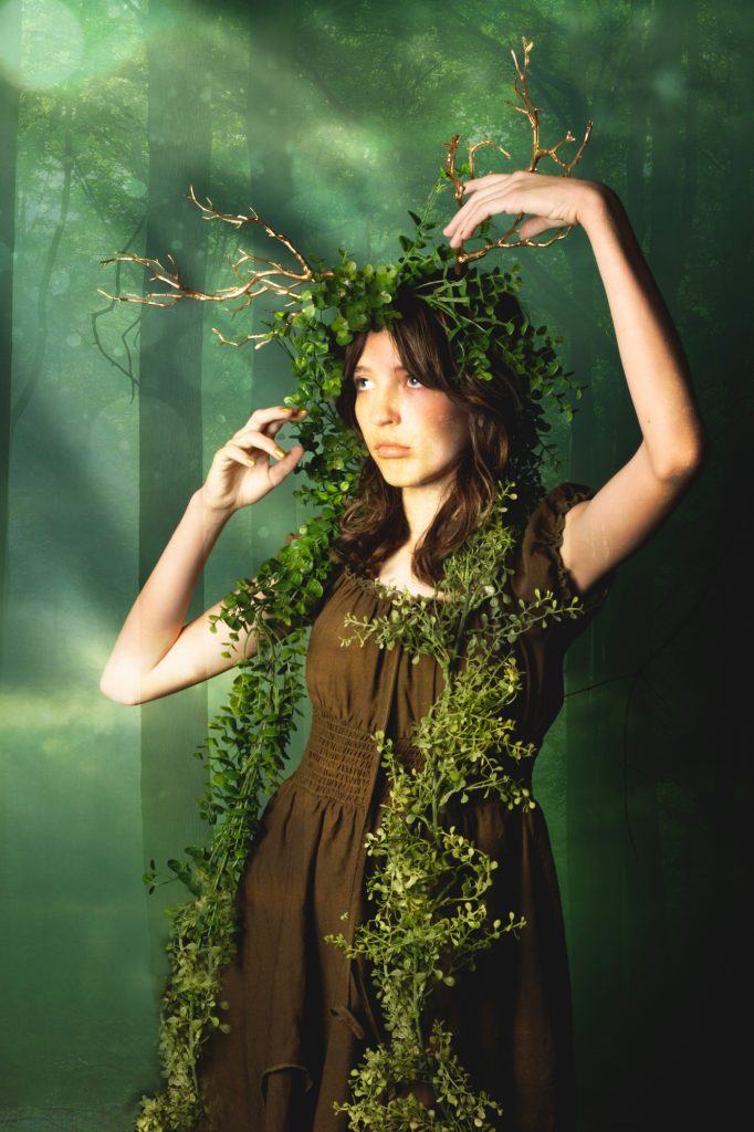 girl with antlers surrounded by forest