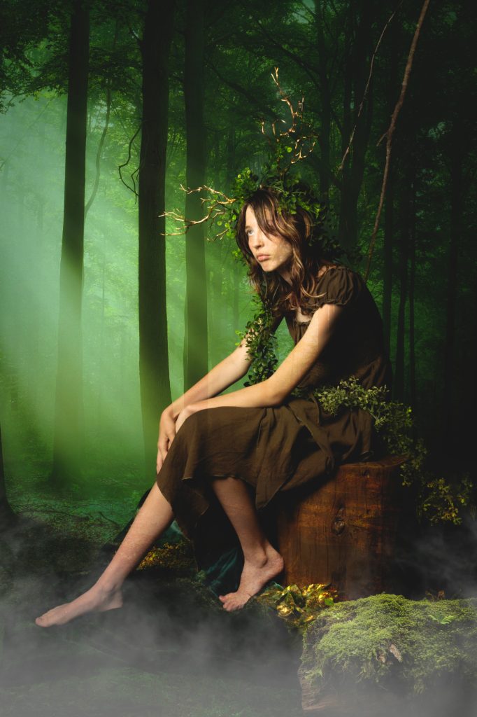 girl sitting on stump in forest